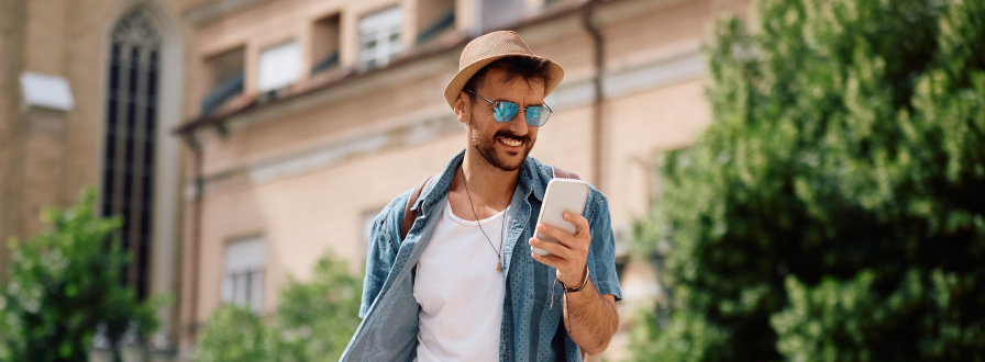 Traveler in city square holding smartphone and luggage, instantly connected to mobile network upon arrival using xeSIM international travel eSIM data plan.